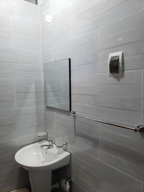 Un baño con lavamanos blanco, espejo y barra para toallas.