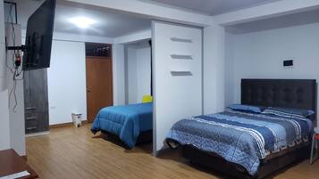 A bedroom with a bed, a desk, a wardrobe, and a television.
