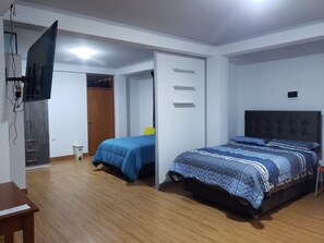 A bedroom with a bed, a desk, a wardrobe, and a television.