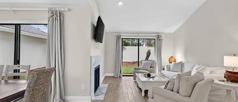 Amplia sala de estar con chimenea, televisor montado en la pared y comedor con mesa y sillas.