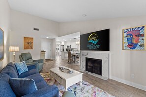 A spacious living room with a fireplace, a dining area, and a kitchen in the background. - New! Sandestin Cottage w/ Golf Cart, Pool, Beach Access, Dog Friendly & Fenced Yard (Miramar Beach)