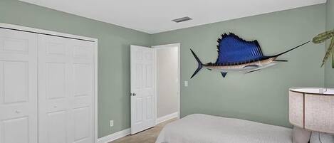 Un dormitorio con cama, un armario blanco, una puerta y un adorno de pez en la pared.