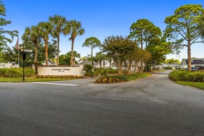 A residential area with a sign for Linkside Village, a paved road, and various trees. - New! Sandestin Cottage w/ Golf Cart, Pool, Beach Access, Dog Friendly & Fenced Yard (Miramar Beach)