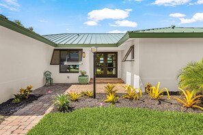A residential property with a paved patio, a green chair, a potted plant, and a well-maintained garden. - Coastal Elegance with Breathtaking Matlacha Pass Views (Matlacha)