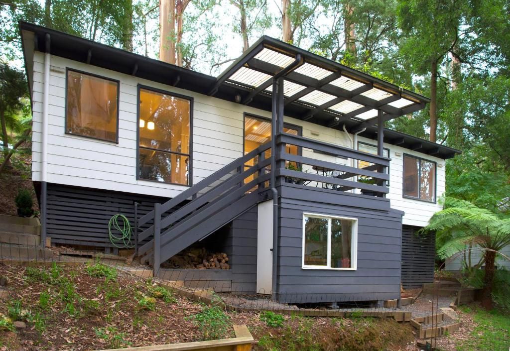 A modern two-story house with a covered outdoor area and a staircase leading to the upper level.