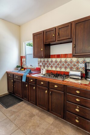 A kitchen with wooden cabinets, a tiled backsplash, a gas stove, a toaster, and a coffee maker. - Casa Cactus with a heated pool for 7 people in Centenario. (El Centenario)