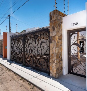 A gated entrance with a stone pillar, a metal decorative gate, and a building number 1250. - Casa Cactus with a heated pool for 7 people in Centenario. (El Centenario)