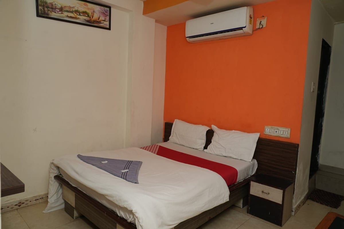 Quarto com cama, mesa de cabeceira, aparelho de ar condicionado e um quadro pendurado na parede.