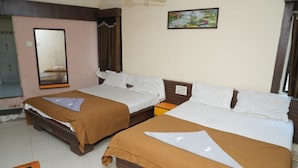Habitación de hotel con dos camas, un espejo grande, un ventilador de techo y una mesita.