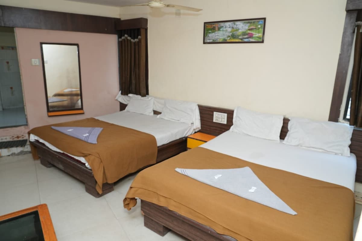 Quarto de hotel com duas camas, um espelho grande, um ventilador de teto e uma pequena mesa.