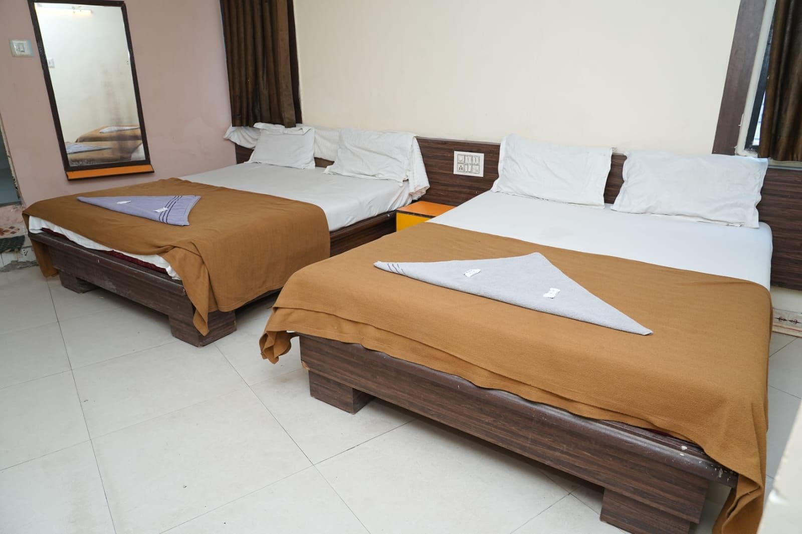 A hotel room with two beds, each with a wooden headboard and white bedding.