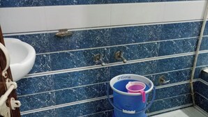 Un baño con un lavamanos blanco, un inodoro azul y un cubo de basura azul.
