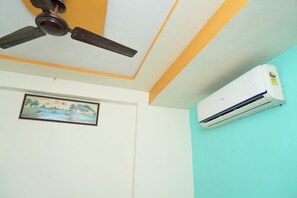 Ein Zimmer mit Deckenventilator, Klimaanlage und einem gerahmten Bild an der Wand.