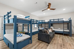 A room with bunk beds, a sofa, and a ceiling fan. - ☀️ Seas the Day | Ocean Views | Steps 2 Beach | Private Pool | Free Golf (Miramar Beach)
