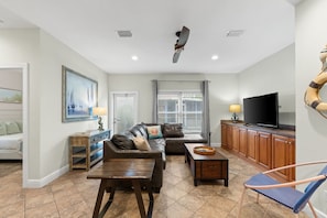 A spacious living room with a sofa, coffee table, and TV. - ☀️ Seas the Day | Ocean Views | Steps 2 Beach | Private Pool | Free Golf (Miramar Beach)
