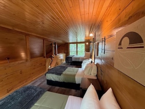 Ein Blockhaus-Interieur mit Holzwänden, zwei Betten, einem Fenster und einer Wandleuchte.