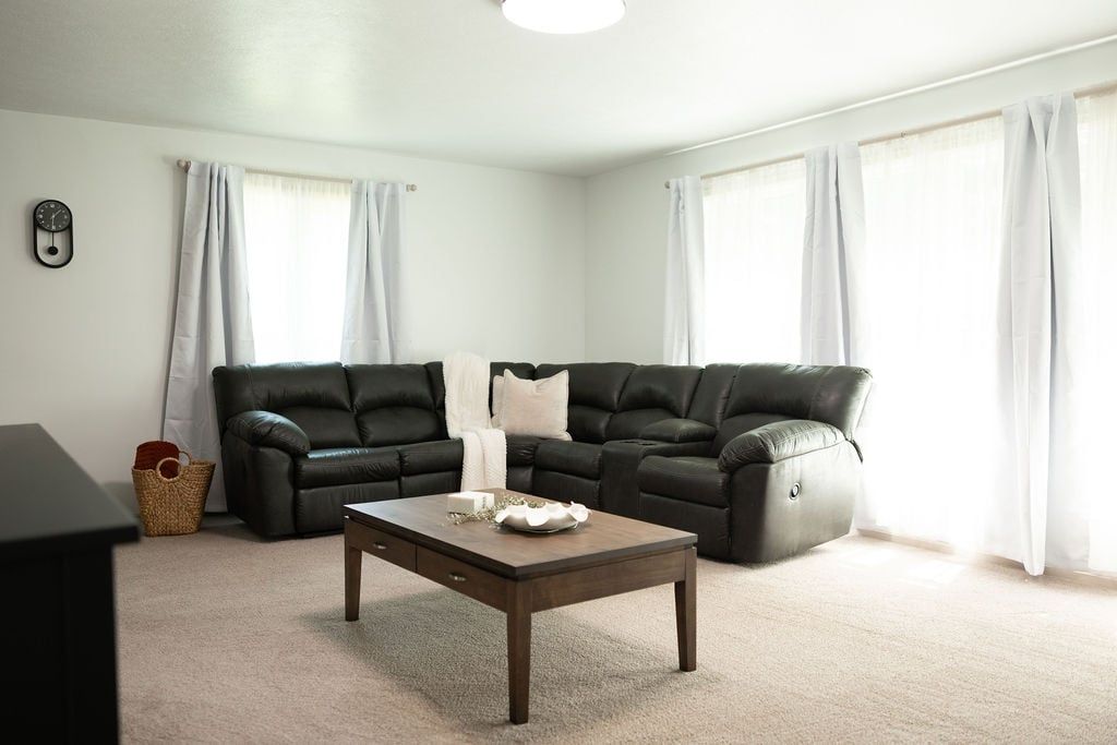 A living room with a dark leather sectional sofa, a wooden coffee table, and a small side table.