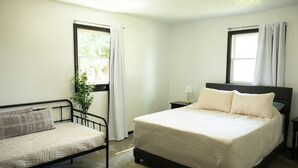 Ein Schlafzimmer mit einem Bett, einem Sofa und einem Fenster mit Vorhängen.