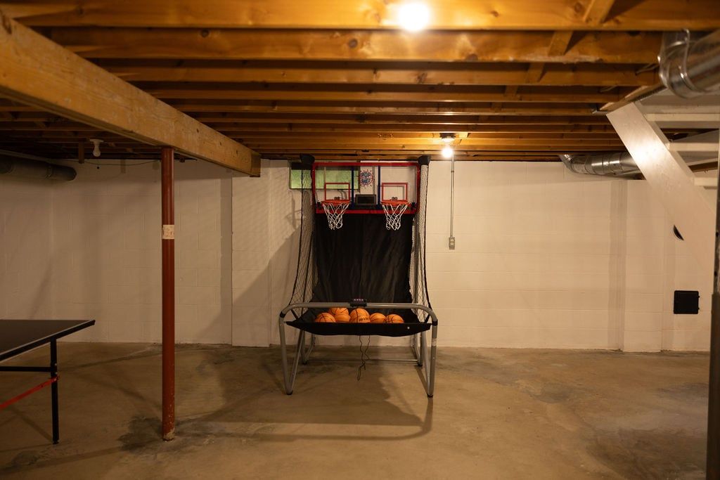 Ein Kellerraum mit einem Basketballkorb, einem Metallregal mit Sportbällen und einem Tischtennis-Tisch.