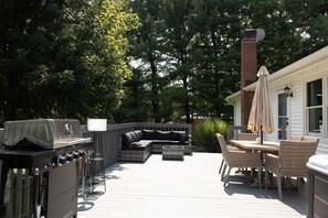 Un patio exterior con una parrilla, zona de estar y una mesa con sillas.
