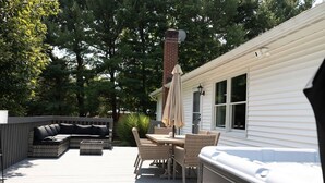 Eine Terrasse mit Gartenmöbeln, einem Whirlpool und einem Kamin.