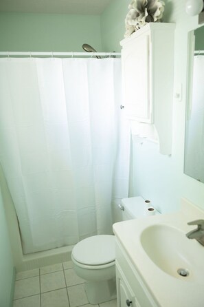 Un baño con inodoro blanco, lavamanos y cortina de ducha.