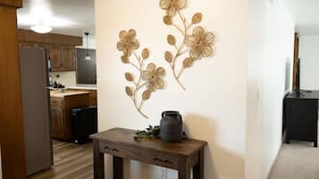 A kitchen with wooden cabinets, a refrigerator, a coffee machine, and a decorative wall piece.