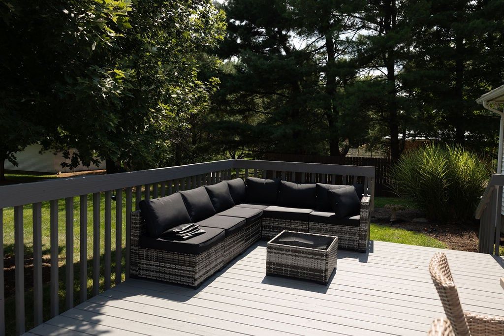 An outdoor deck with a sectional sofa and a small table.