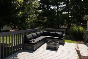 An outdoor deck with a sectional sofa and a small table.