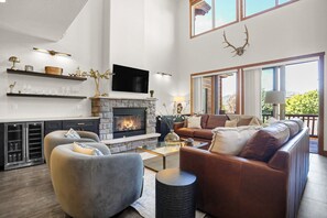 A spacious living room with a stone fireplace, leather sofas, and a flat-screen TV mounted above it. - New Listing - Looping Ski Shuttle - Mountaineer Manor (Steamboat Springs)