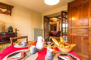 Desayuno preparado para dos personas, con pan, bollería y una jarra.