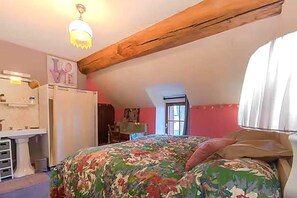 Un dormitorio con cama, cómoda, tocador y ventana con cortinas.