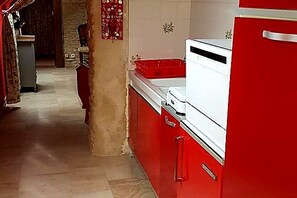 Una cocina con armarios rojos, un refrigerador blanco y un lavamanos rojo.