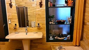 A bathroom with a sink, mirror, and bathtub. There is a shelf with decorative items and a trash can. - 2 vacation rentals in Burgundy for 11 people Nature, optional spa, and pets welcome! (Recey-sur-Ource)