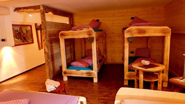 Una cabaña de madera con literas, una mesita y un cuadro en la pared.
