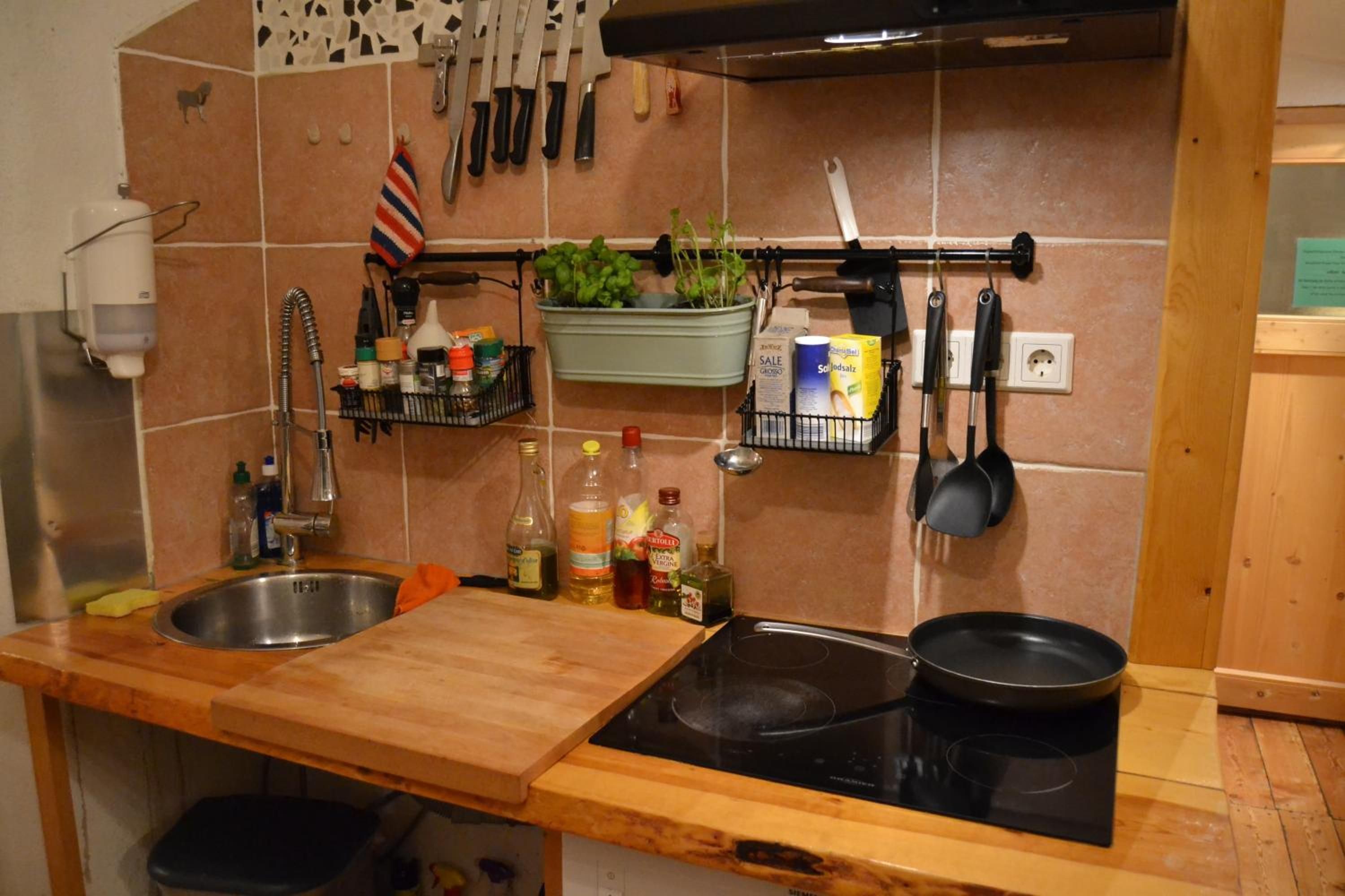 A kitchen with a double sink, a stove, and various kitchen utensils and appliances.