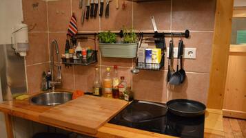 A kitchen with a double sink, a stove, and various kitchen utensils and appliances.