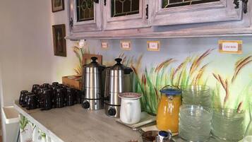 A kitchen counter with coffee makers, a kettle, and various containers for food items.