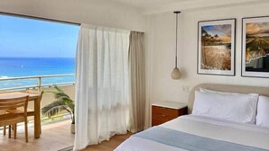 A hotel room with a large bed, a desk, and a view of the ocean. - NEWLY Remodeled - Oceanfront Paradise (Honolulu)