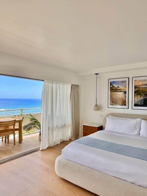 A hotel room with a large bed, a desk, and a view of the ocean. - NEWLY Remodeled - Oceanfront Paradise (Honolulu)