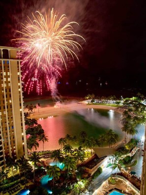 A resort with a beachfront, a pool area, and fireworks in the sky. - NEWLY Remodeled Oceanfront Fireworks Every Friday (Honolulu)