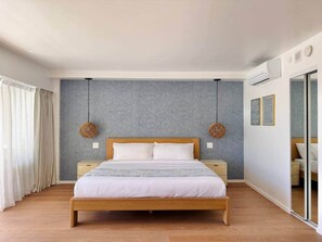 A modern bedroom with a wooden bed, a grey textured wall, and a large window with curtains. - NEWLY Remodeled Oceanfront Fireworks Every Friday (Honolulu)