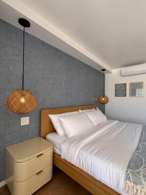 A bedroom with a bed, bedside tables, and wall-mounted lamps. - NEWLY Remodeled Oceanfront Fireworks Every Friday (Honolulu)