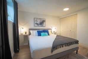 Ein Schlafzimmer mit einem Bett, Nachttischen, einer Wandleuchte und einer Tür.