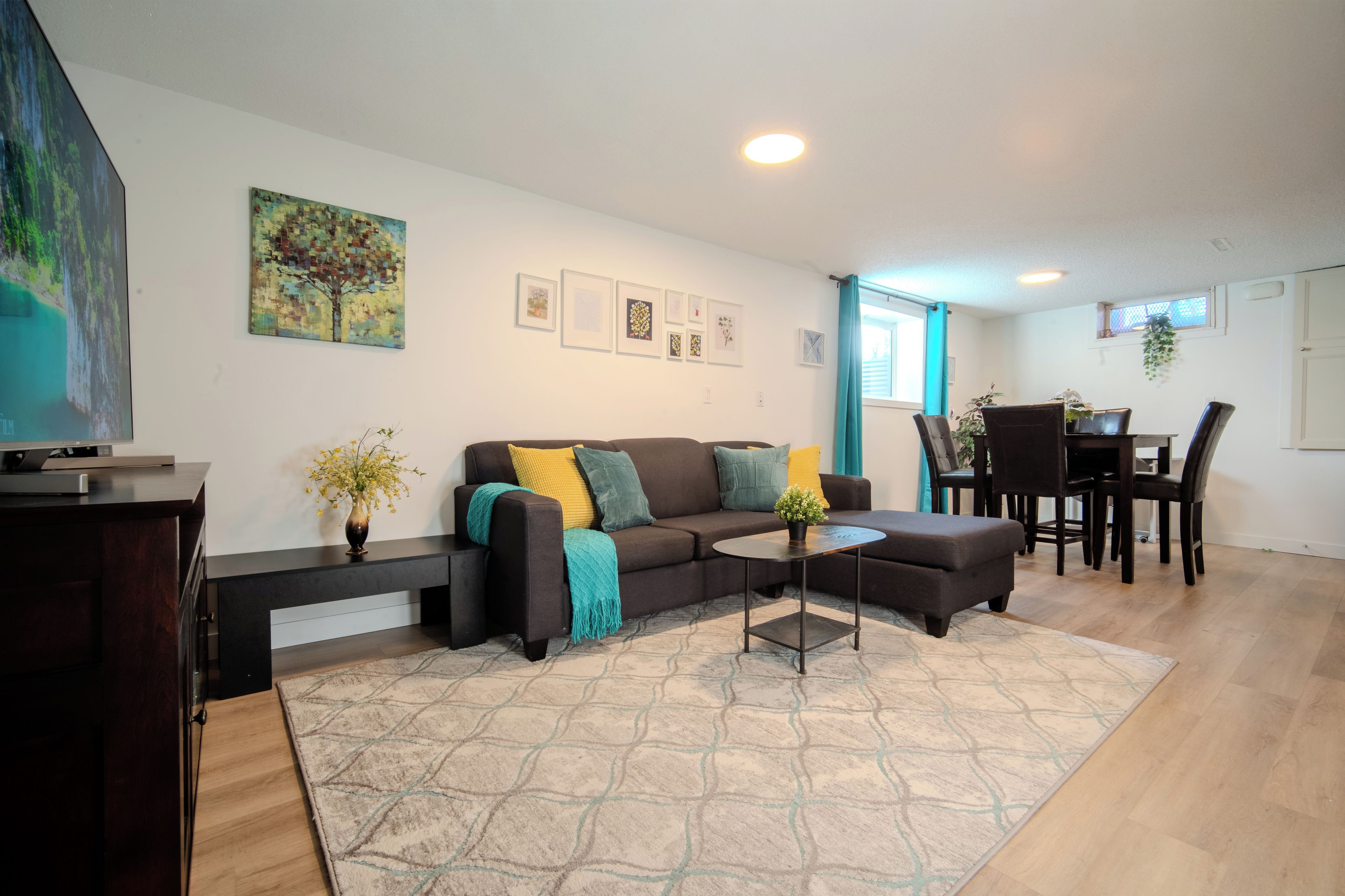 A modern living room with a sofa, coffee table, and a dining area with chairs and a table.