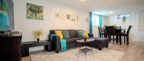 A modern living room with a sofa, coffee table, and a dining area with chairs and a table.