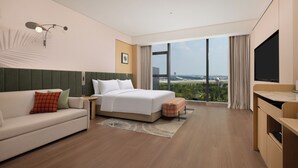 A hotel room with a bed, a sofa, a TV, and a view of the airport. - Hilton Garden Inn Chengdu Shuangliu International (Chengdu)