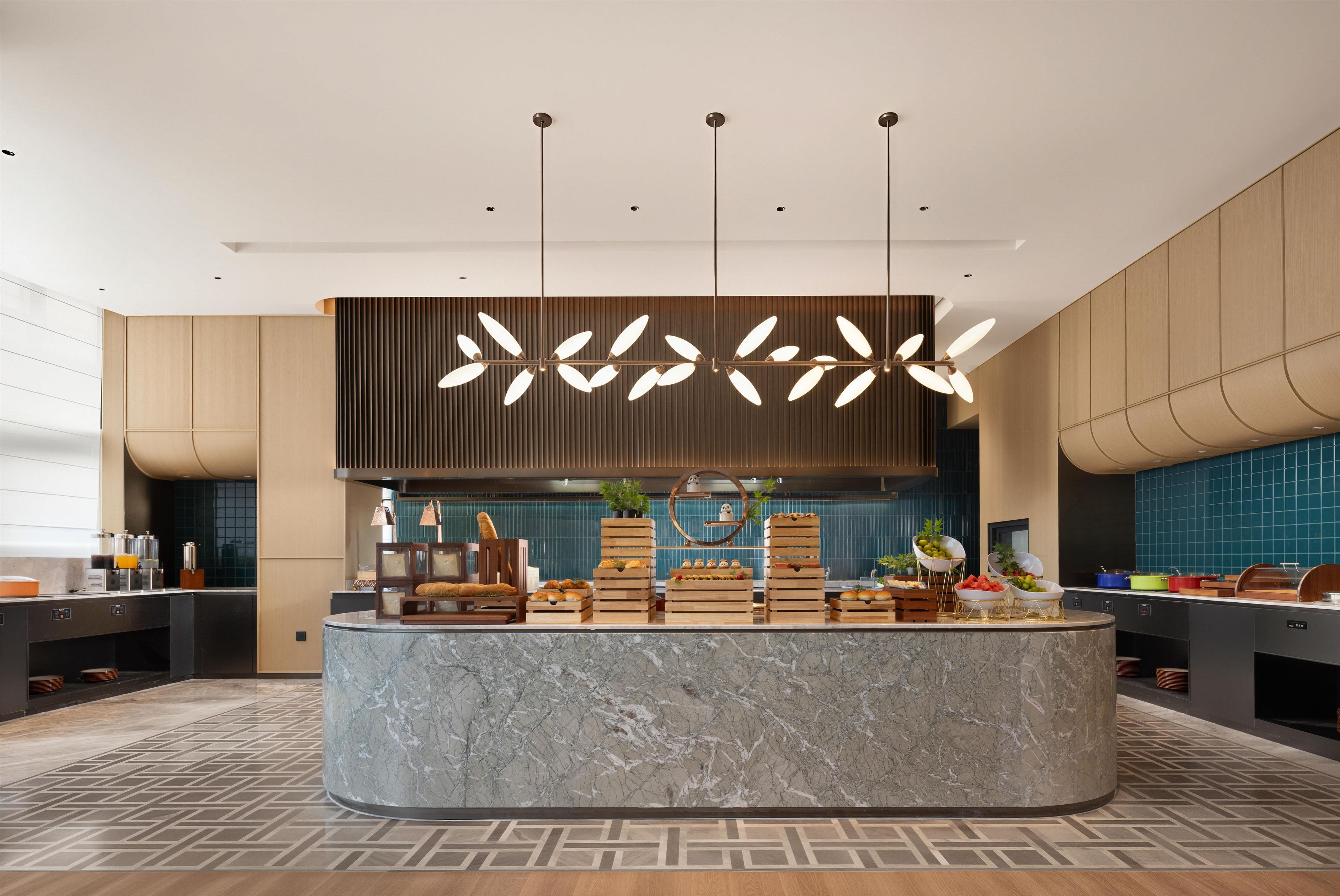 A modern kitchen with a marble island, pendant lighting, and a variety of food items displayed on the counter.