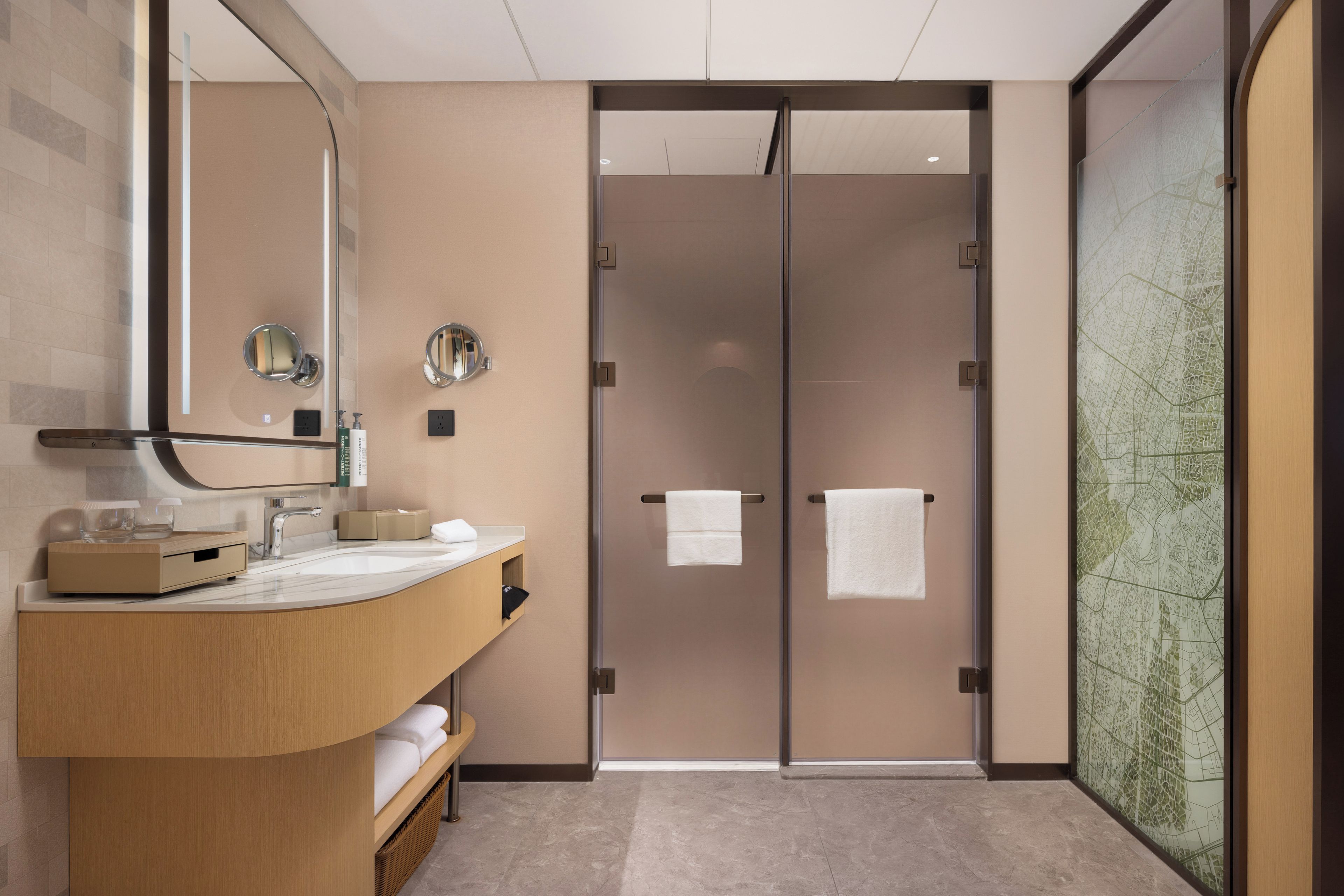 A modern bathroom with a curved vanity, a large mirror, and a glass door leading to a shower area.