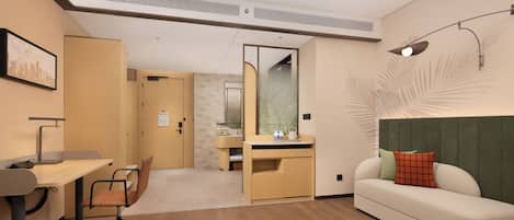 Habitación de hotel moderna con escritorio, silla, sofá y espejo.